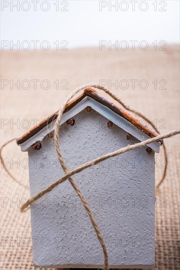 Thread wrapped around a model house on a brown background