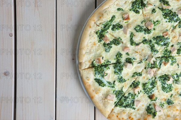 Top view of half of pizza with spinach and chicken. Copy paste space