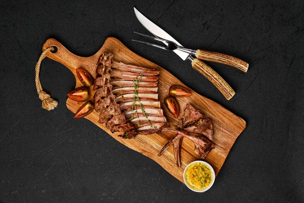 Overhead view of grilled ribs of lamb on a plate with spicy sauce