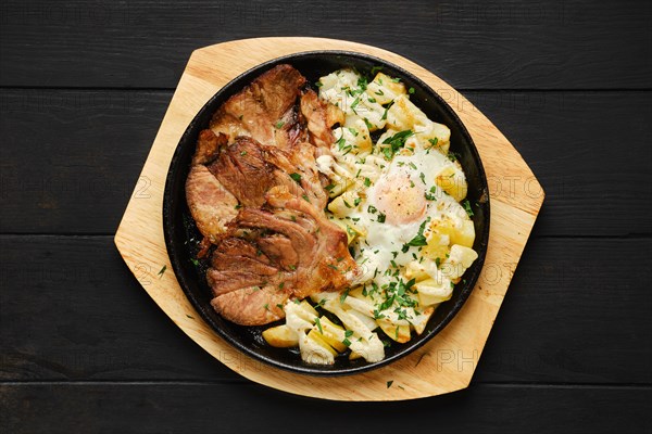 Top view of fried pork t-bone chop with potato and egg on a plate