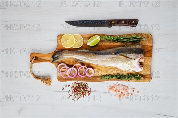 Fresh gutted and headless cod carcass on wooden cutting board