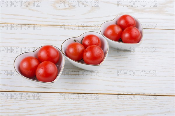 Red ripe cherry tomatos tomatos in heart shaped bowl