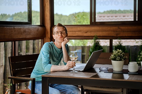 Funny man sits behind the table with laptop