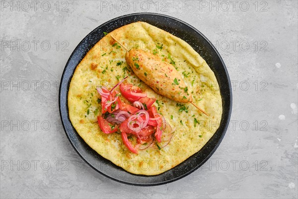 Top view of kebab served on tortilla with tomato and red onion