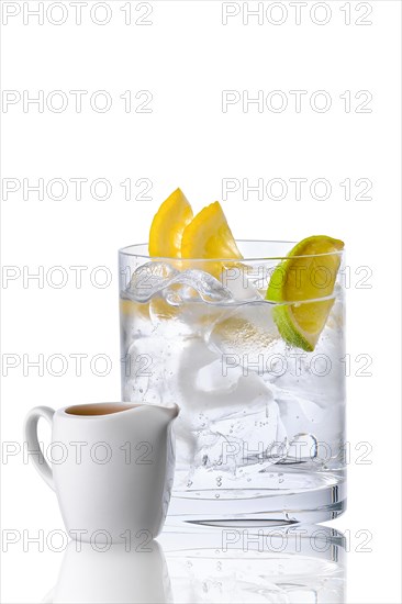 Glass with tonic and ice served with espresso in porcelain jug isolated on white background