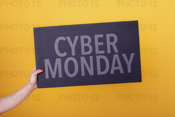 Female hand holding a cyber monday poster. Studio shot