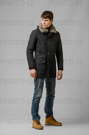 Full length portrait of handsome man in warm winter coat posing in studio