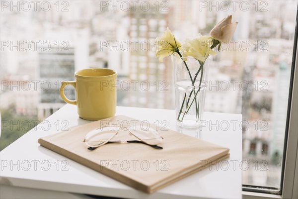 Glasses book near flowers mug table