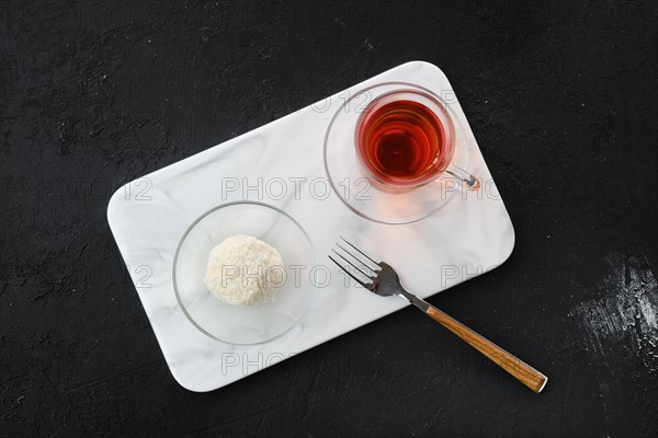 Top view of coconut biscuit dough cake and a cup of tea on a table