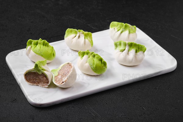 Frozen dumplings stuffed with pork meat and provencal herbs on marble serving plate