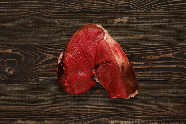 Overhead view of raw deer boneless ham over wooden background