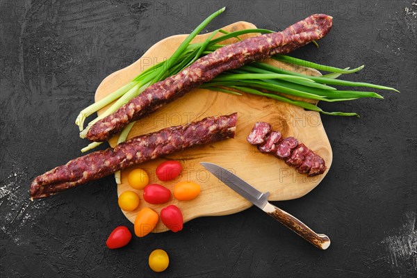 Overhead view of sun-dried pork sausage on wooden cutting board