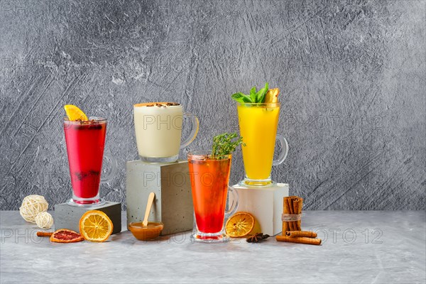 Composition with hot fruit and herbal winter drinks on shabby grey background
