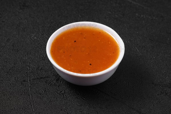 Small bowl with spicy orange sauce for poultry