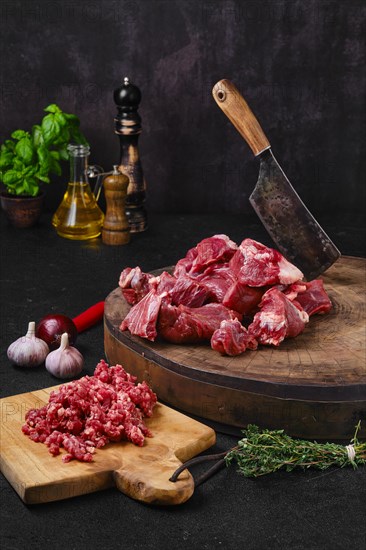 Chopping fresh beef meat for goulash or stew on wooden chopping stump