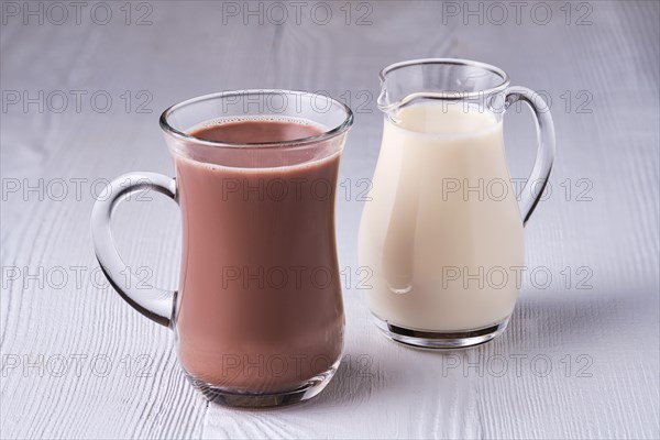 Cup of cappuccino and small creamer on wooden table