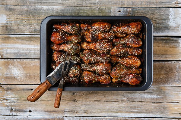 Baked chicken legs with spicy sauce on a baking tray