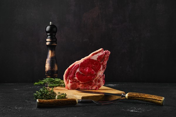 Raw strip steak bone in on dark background