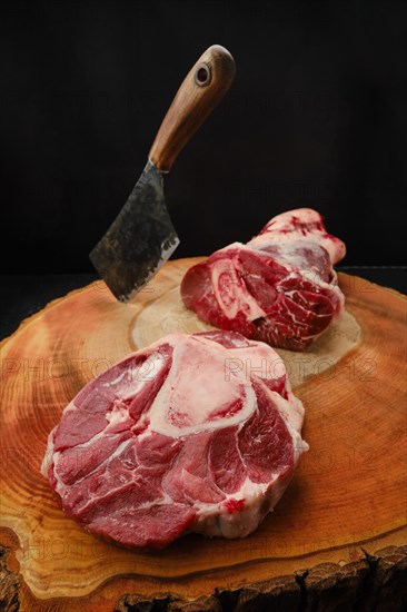 Chopping ossobuco steak from beef shank with cleaver on wooden stump