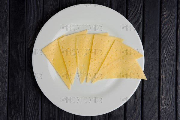 Top view of cheese slices on round plate on wooden table