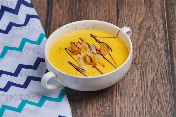 Plate of pumpkin soup on wooden table