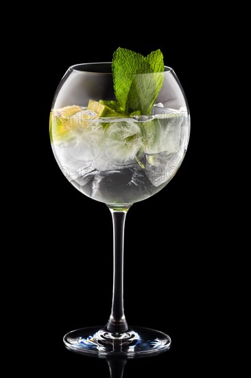 Big round wine glass with fresh cold lemonade isolated on black background