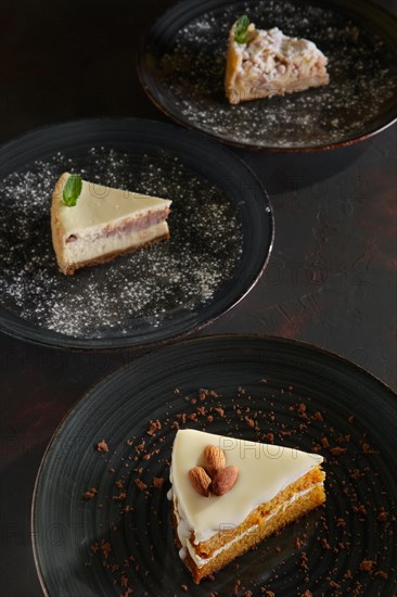 Three pieces of homemade cakes on a dark wooden vintage background