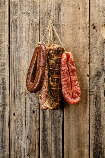 Assortment of dried meat and sausages hanging on a barn wall