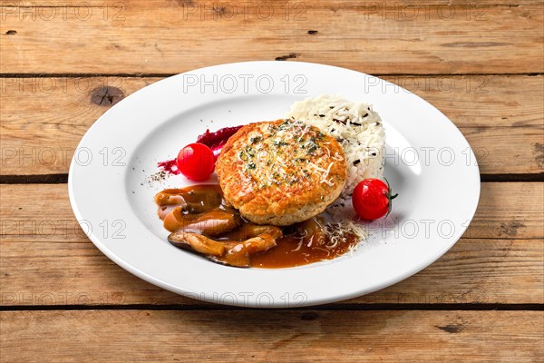 Beef cutlet with rice and mushroom sauce on rustic table