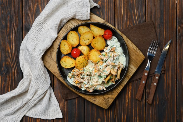 Top view of potato wedges with chanterelles and pork in cast iron skillet