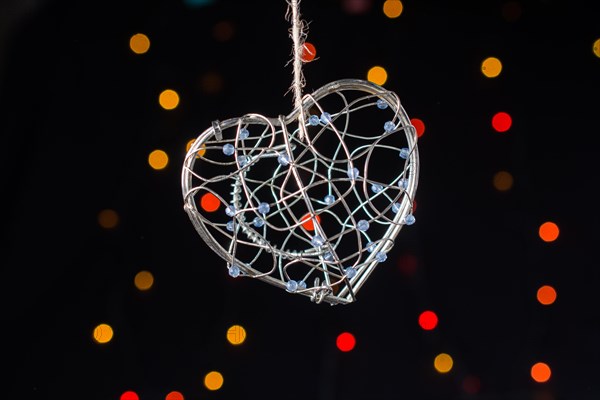 Heart shaped metal cage on a bokeh light background