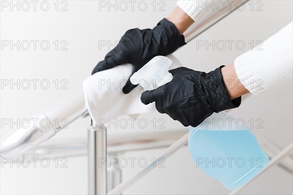 Hands with gloves disinfecting hand rail