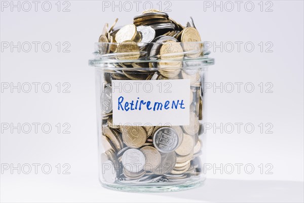 Retirement glass container full coins white backdrop