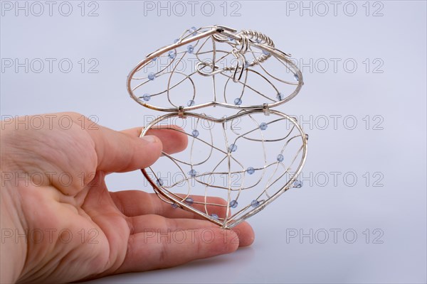 Heart shaped silver color metal wire cage in hand