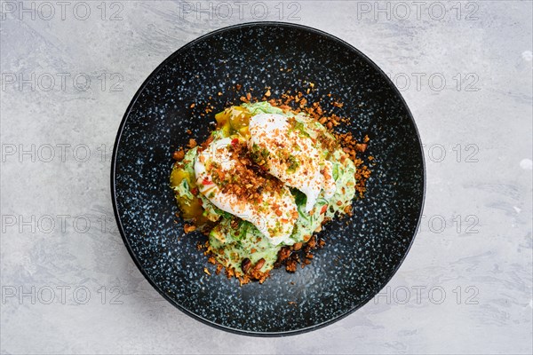 Top view of poached egg on a bun with avocado on a plate