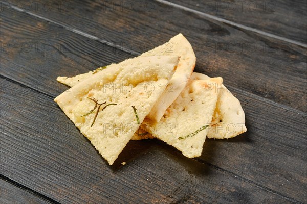 Four pieces of focaccia with herbs on wooden table