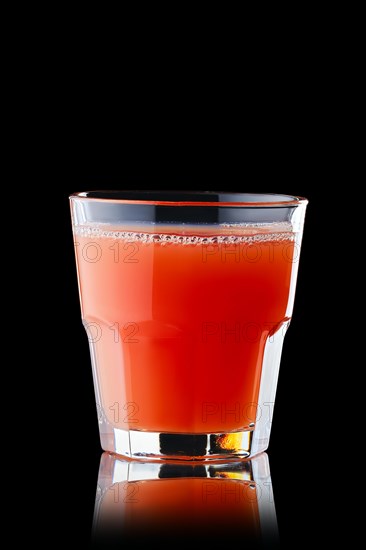 Fresh grapefruit juice in rocks glass isolated on black background