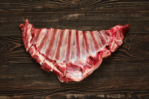 Overhead view of raw fresh deer ribs over dark wooden background