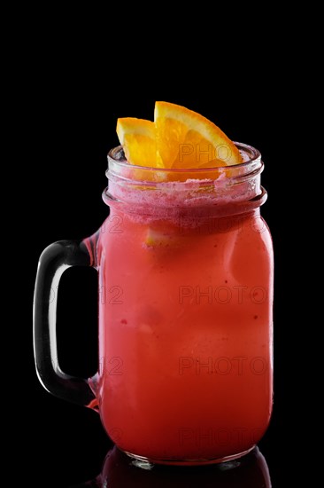 Mug with strawberry and orange cocktail isolated on black background