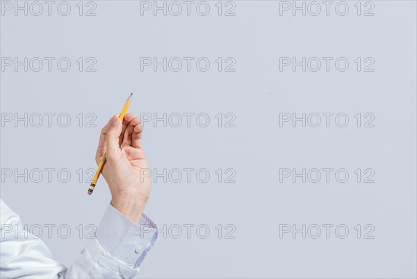 Hand with a pencil pointing at a blank space. Male hand holding a pencil on a blank. Man fingers holding a pencil with blank space. Person's hands holding a pencil on a space for text