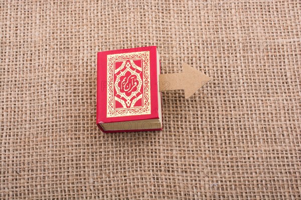 Paper arrow and Islamic Holy Book Quran in mini size