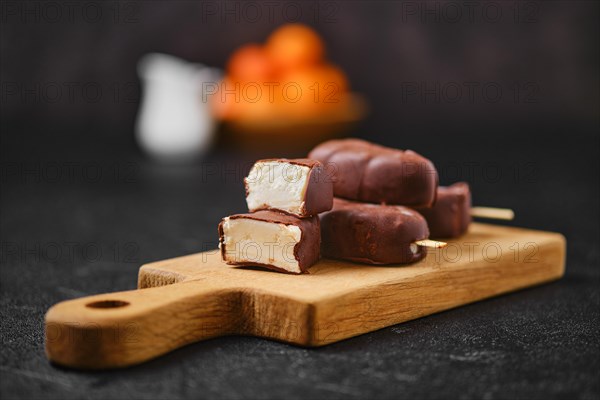 Homemade curd bars in chocolate on wooden board