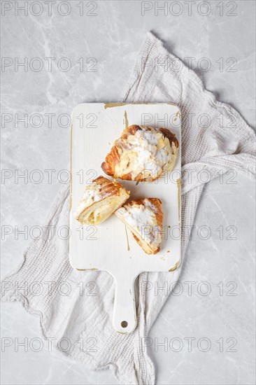 Top view of fresh croissant with caramel and peanut shavings on wooden serving board