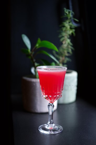 Soft focus photo of scofflaw cocktail on bar counter. Image with shallow depth of field and contains a little noise due to poor lighting conditions