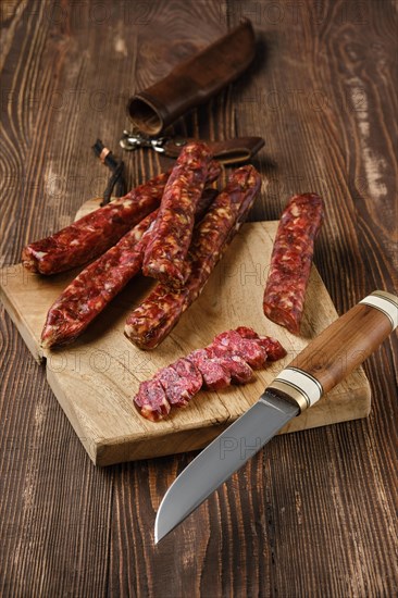 Dried jerked deer and pork sausage on wooden background