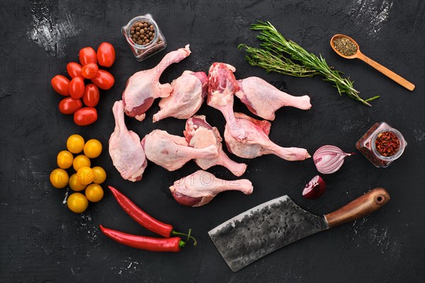 Raw duck drumstick with spice and herbs on black concrete background