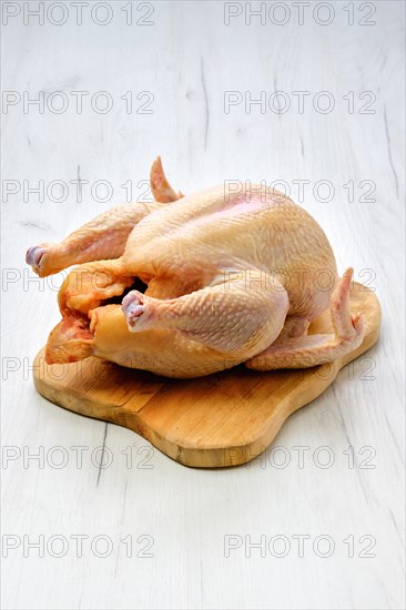 Fresh raw whole farm chicken on wooden cutting board