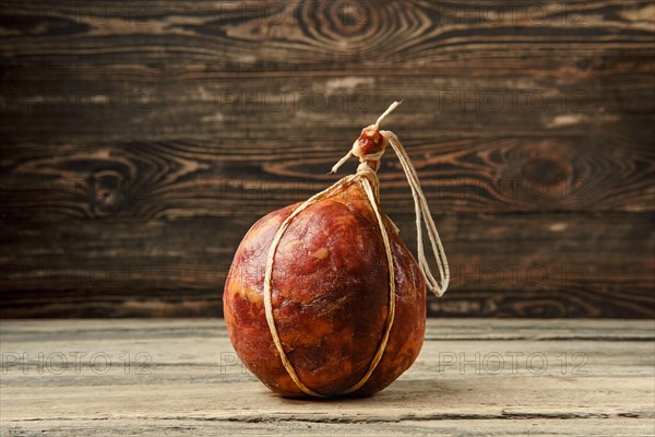 Round fermented beef sausage on wooden table