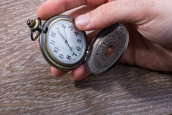 Retro style pocket watch in hand on black background