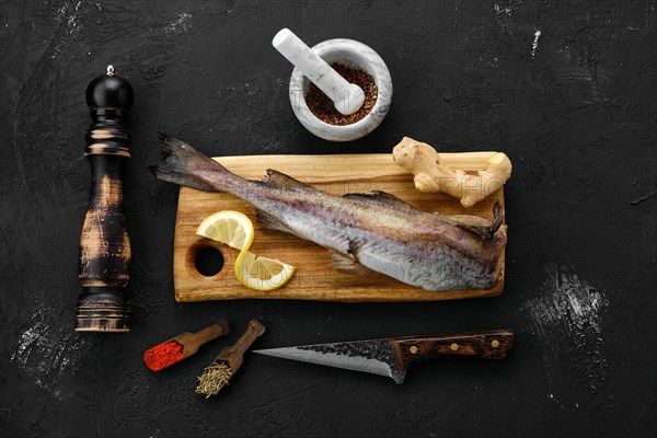 Raw fresh frozen pollock carcass with spices on cutting board